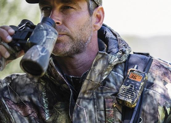 man in camo looks into binoculars with camo walkie talkie