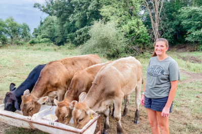 woman stands by 4 cows