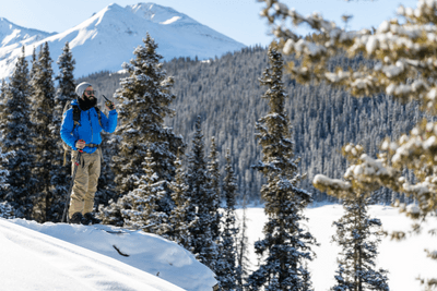 skier stands on snowy hill with walkie talkie