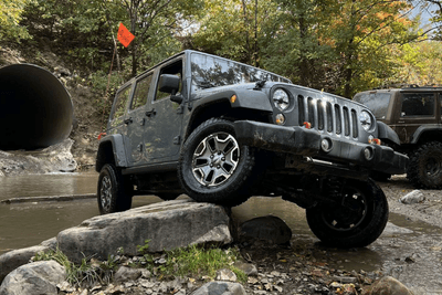 Jeep has front passenger wheel up on rock