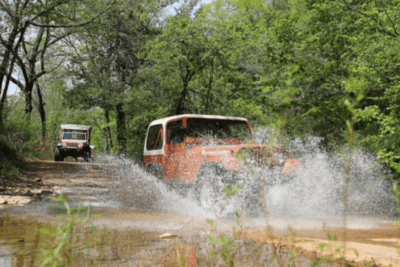 Jeep crosses water on trail in forest