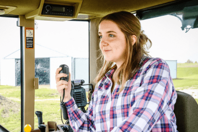 woman in plaid shirt in combine cab holds MicroMobile mic