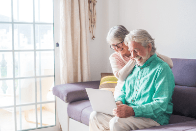 elderly couple looks at laptop