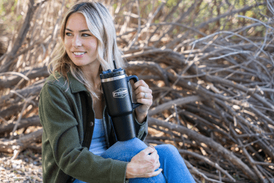 woman sitting near branches with Midland-branded tumbler