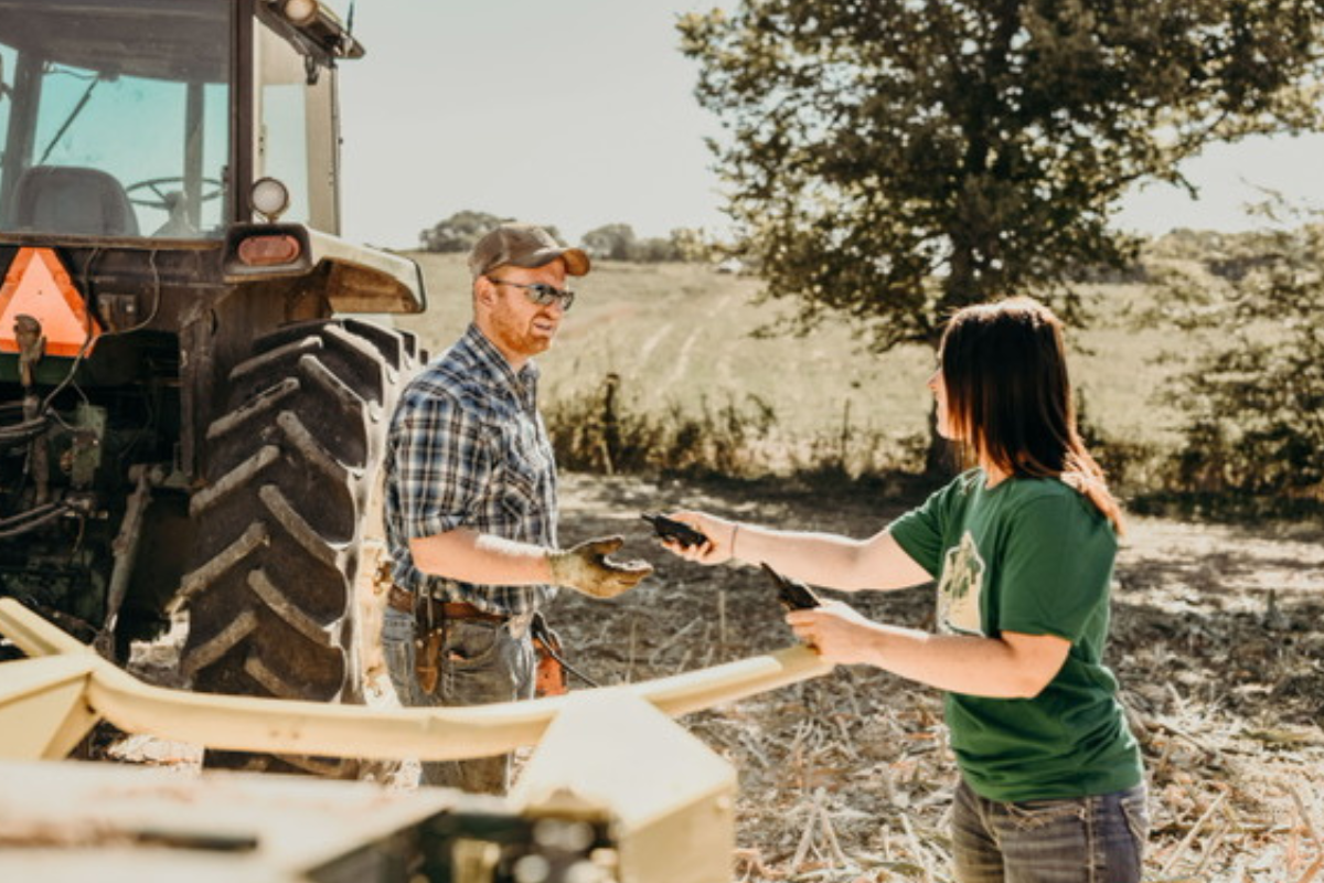 husband and wife stand by tractor