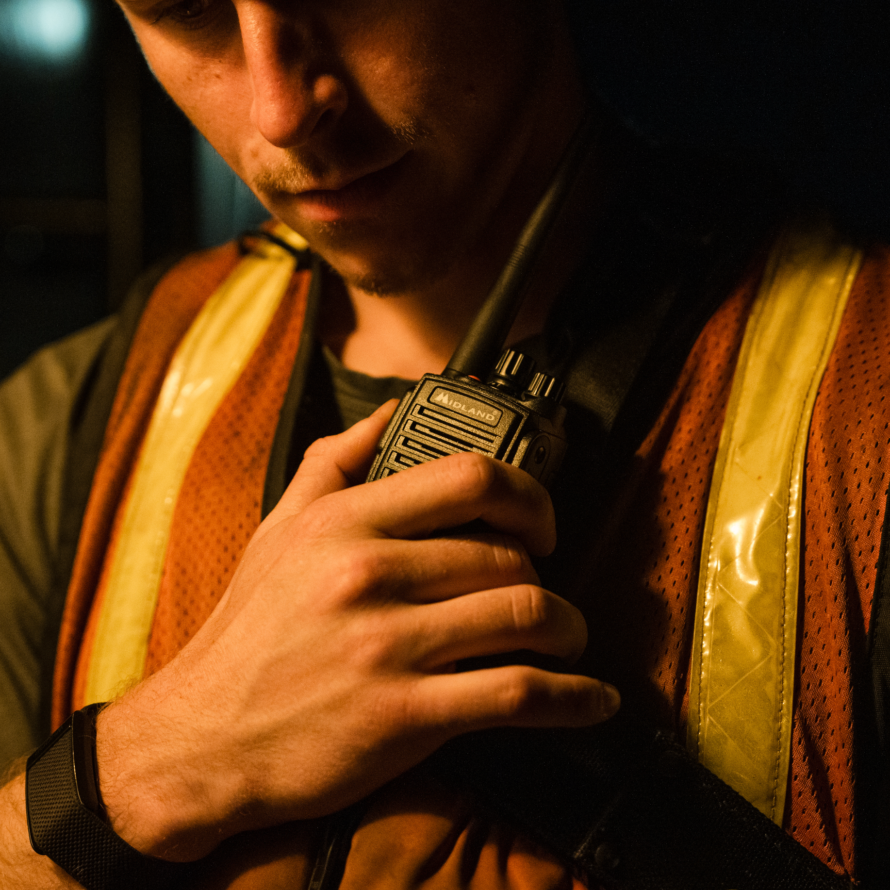 Man holding a walkie-talkie in a dimly lit setting