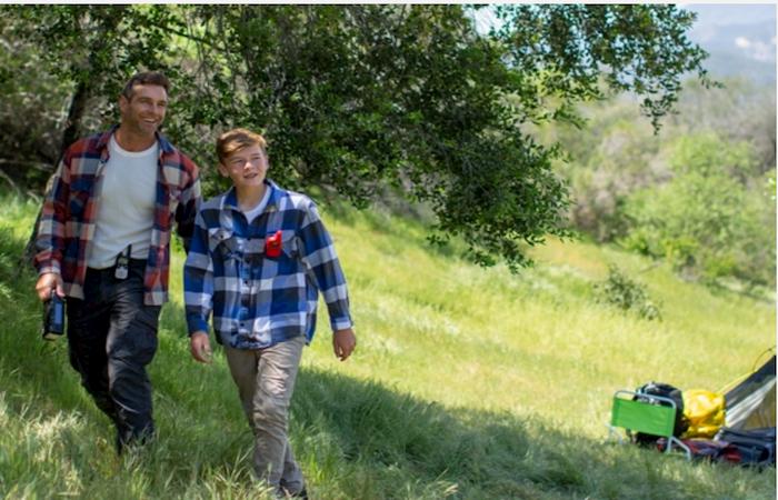 father and son walk in field with walkie talkies
