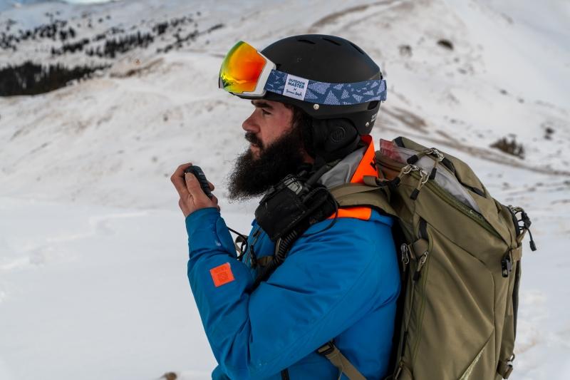 man uses walkie talkie on snowy mountain