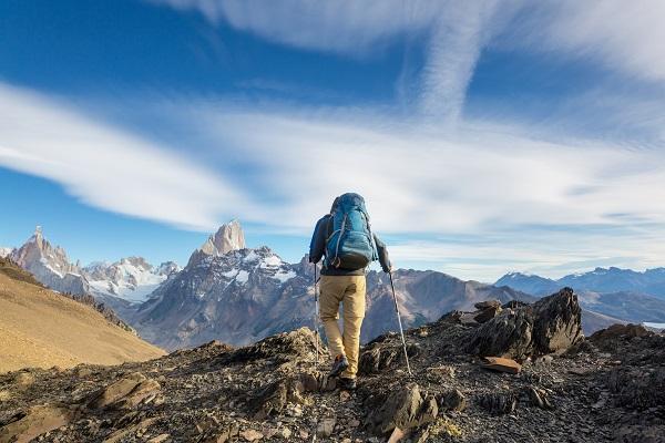 man hikes to mountain peak
