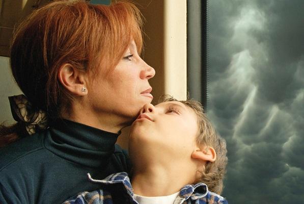mom and son sit by window with stormy sky