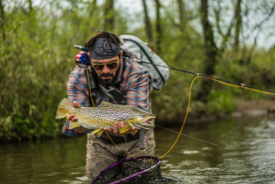 fly fisher holds fish
