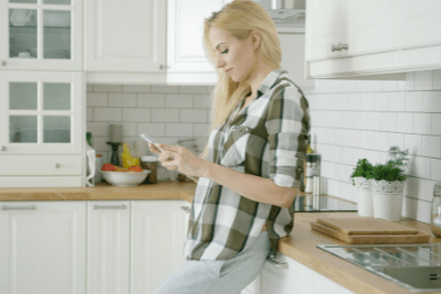 woman stands on phone in kitchen