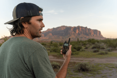 man uses walkie talkie by mountain