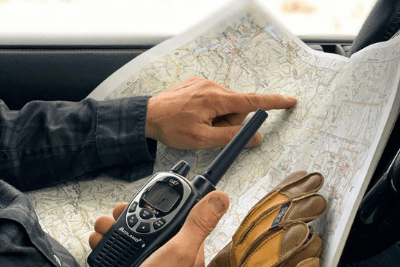 hands point at map while holding walkie talkie