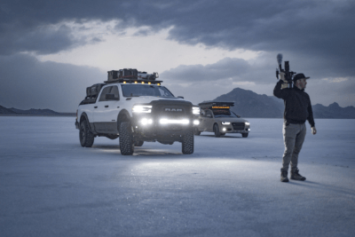 two overlanding vehicles lights up night with man holding camera