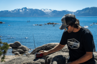 man on rock with emergency radio