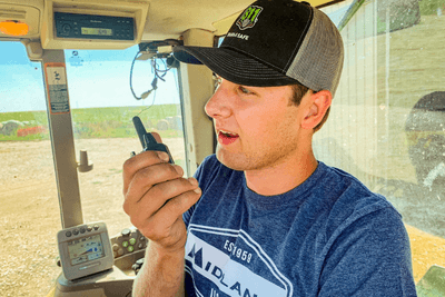 man uses walkie talkie in tractor cab