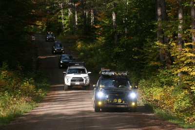 Subaru overlanding vehicles on trail in forest