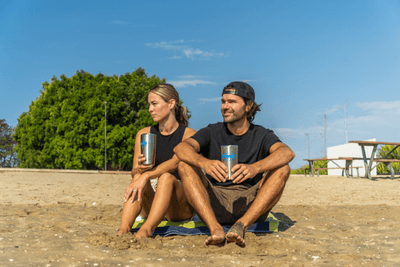 couple sitting on beach with Midland tumblers