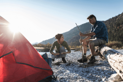 couple uses emergency radio on rocks near their tent