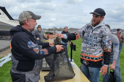 man hands prize to another man at event
