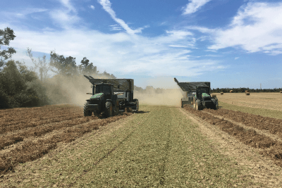 two tractors run side by side in field on farm