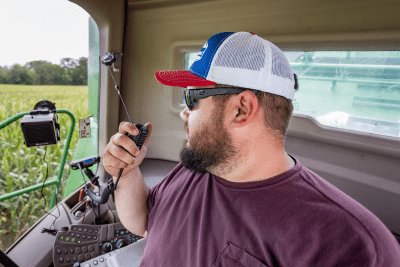 man holds MicroMobile mic in cab of combine on farm