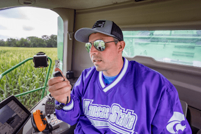 man holds radio microphone in the cab of a combine