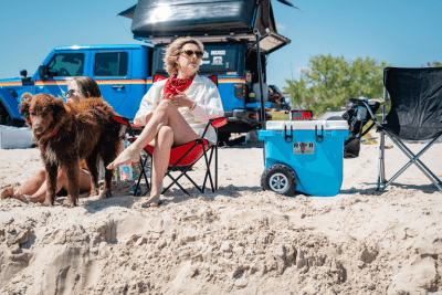 woman and dog sits on beach