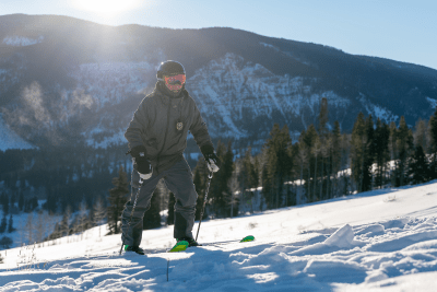 man climbing snowy hill with skis