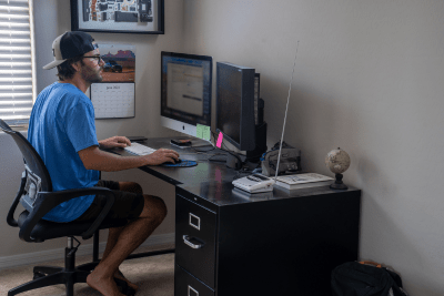man works at home desk with NOAA Weather Radio on it