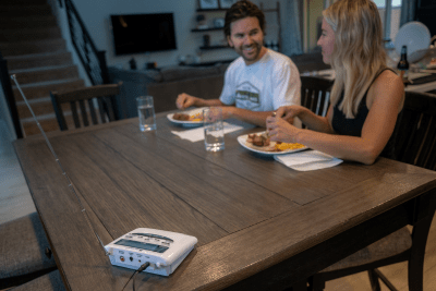 man and woman eat dinner at table with NOAA Weather Radio