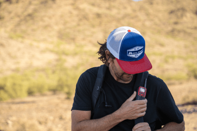 man wearing Midland hat with red walkie talkies and stands by field