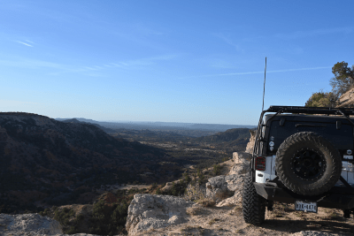 Jeep with Midland antenna sitting on rocky terrain overlooking valley and mountains