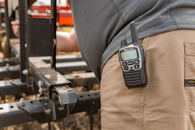 walkie talkie on hip of farmer inspecting machinery