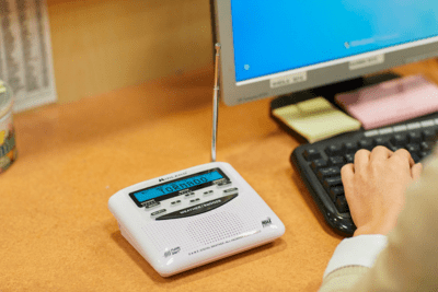 NOAA Weather radio at desk as woman types in office