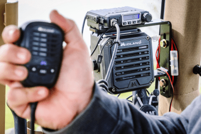 close up of Midland MicroMobile, mic in hand, and external speaker in tractor cab
