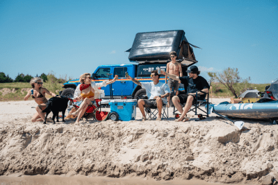 friends sit on beach in circle with emergency radio