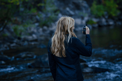 woman holds walkie talkie by mountains