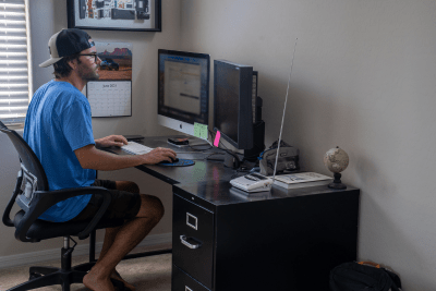 man works at desk with NOAA Weather Radio