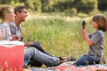 family sits outdoors with emergency radio