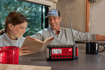 man and young girl sit at table with emergency radio
