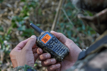 man holds camo walkie talkie