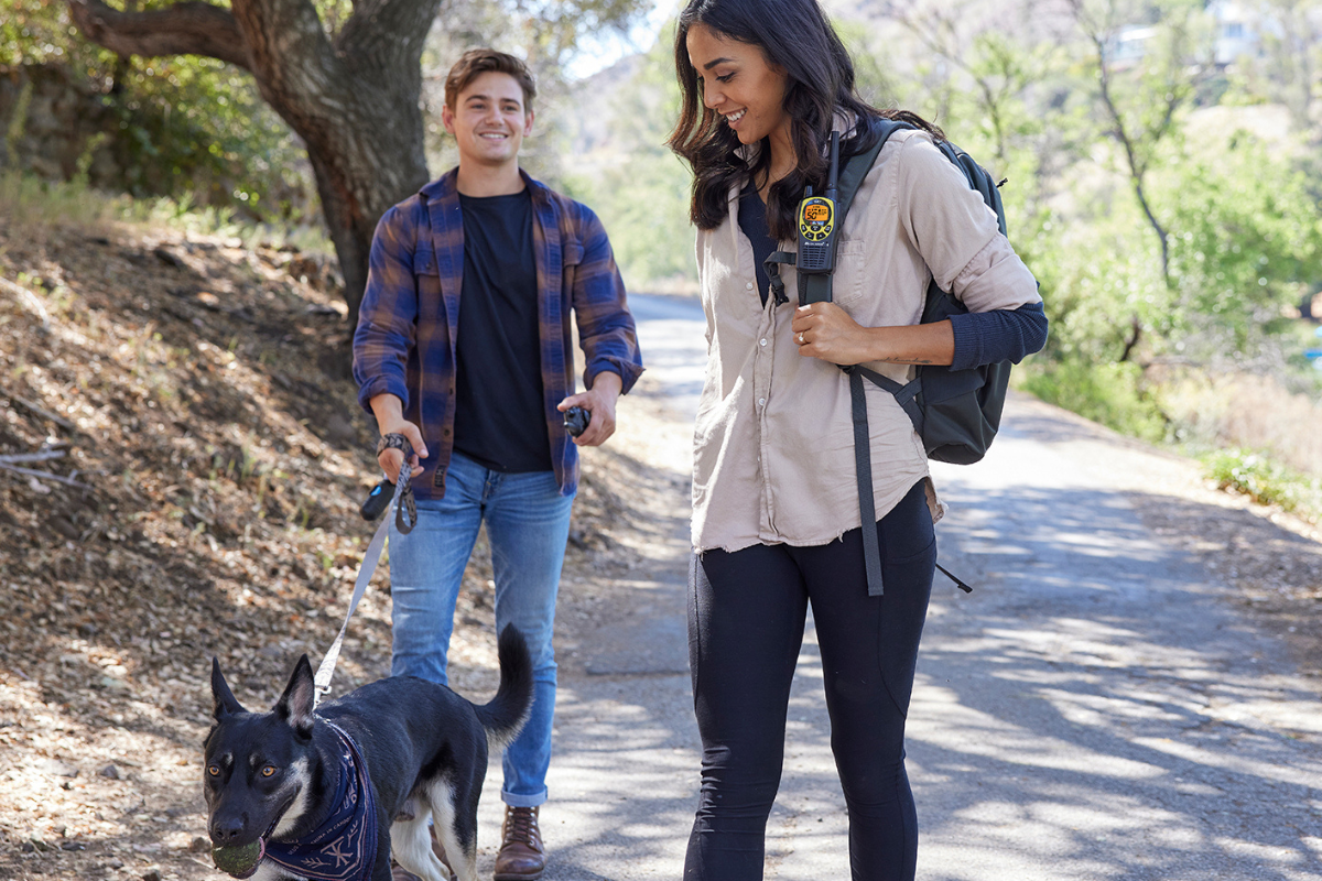 man and woman walk dog with walkie talkie