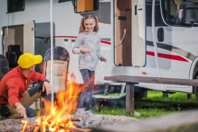 dad and daughter outside RV by campfire