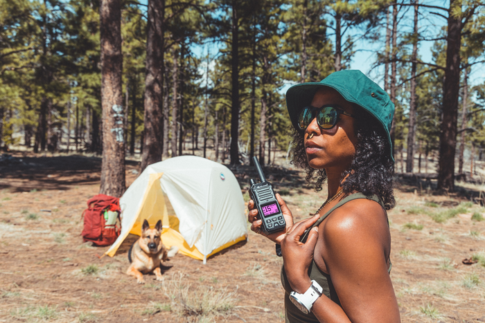 woman holds walkie talkie at campsite
