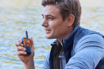 man holds walkie talkie by water