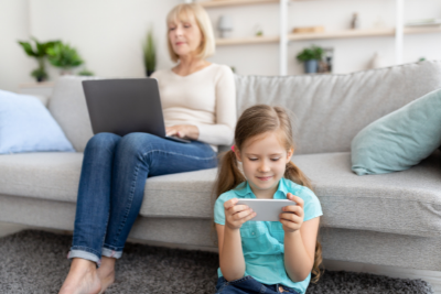mom and kid look at laptop and cell phone