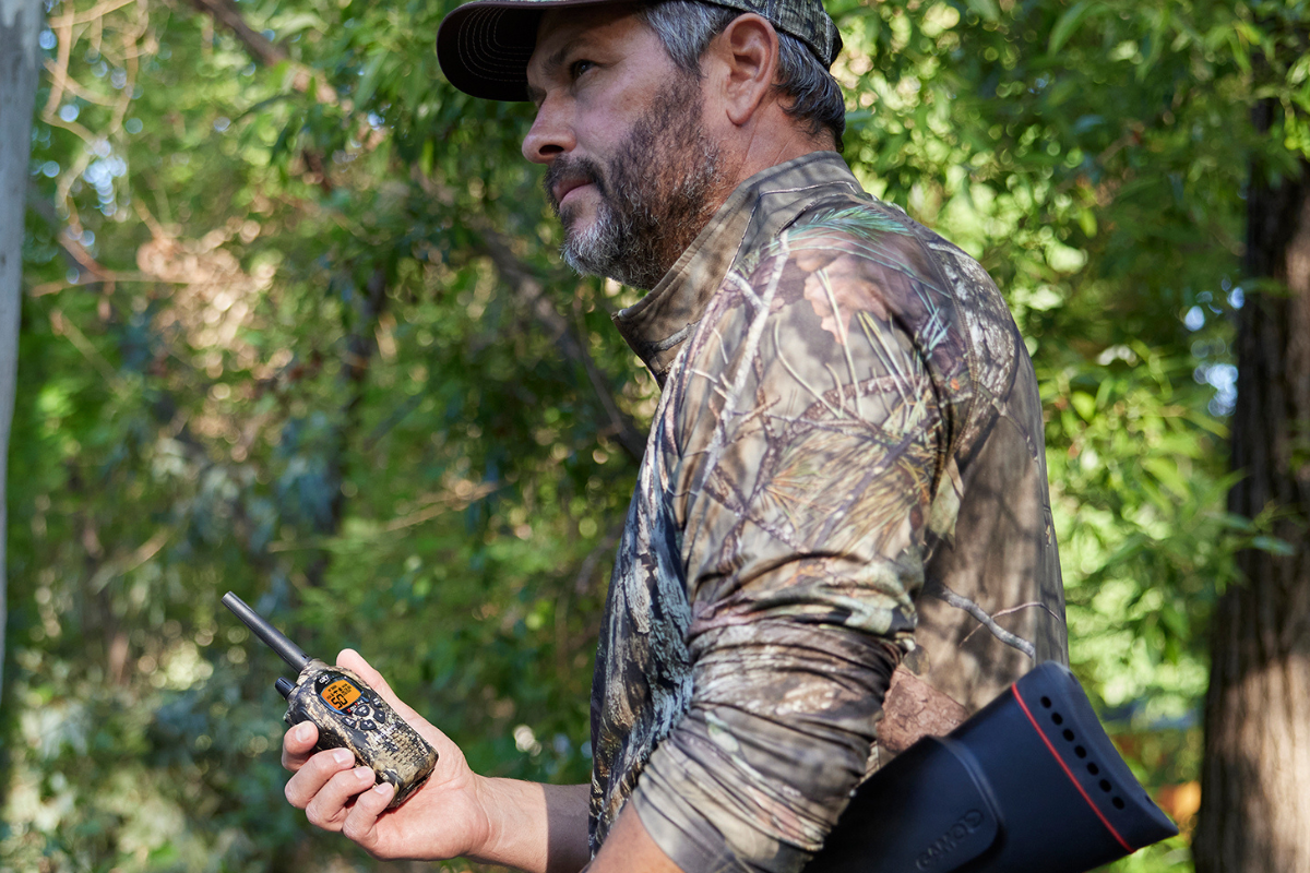 man in woods with camo walkie talkies