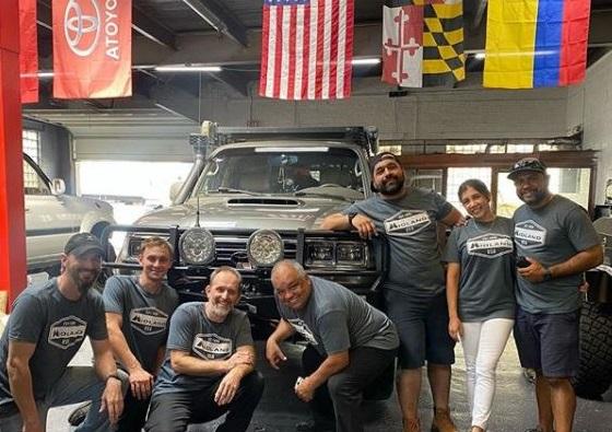 group stands in front of vehicle